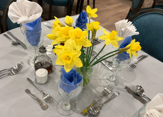 Dining table decorated with yellow daffodils and blue napkins at Holbeach Meadows Care Home in Holbeach, Lincolnshire.